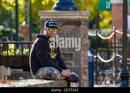 Frederick, MD, USA 10/14/2020: Ein bärtiger Kaukasianer im mittleren Alter sitzt an einer Wand an der Straße. Er ist verkleidet mit batman-Filmcharakter es Stockfoto