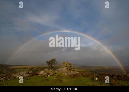 Dartmoor National Park, Devon, Großbritannien. Oktober 2020. UK Wetter: Ein voller Regenbogen erscheint am Himmel über dem legendären Holwell Tor am Dartmoor nach heftigen Regenschauern und sonnigen Zaubersprüchen, die ein deutlich herbstliches Gefühl in den Tag bringen. Kredit: Celia McMahon/Alamy Live Nachrichten Stockfoto