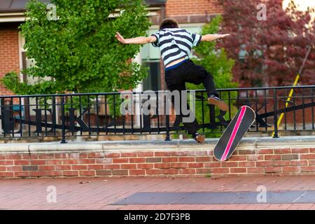 Ein Teenager Skateboarder versucht einen ollie Sprung auf dem Bürgersteig. Er verliert sein Gleichgewicht und fällt vom Skateboard. Er trägt keine Schutzkleidung. Bild Stockfoto