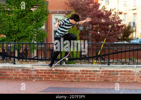 Frederick, MD, USA 10/14/2020: Ein kaukasischer Teenager mit T-Shirt und Trainingshose übt mit seinem Skateboard einen ollie-Sprung. Er versucht zu ju Stockfoto