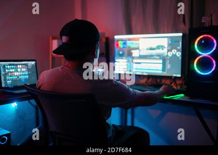 Blogger arbeiten Bearbeitung von Videomaterial und Blick auf den Monitor In-Home Office während der Post-Production für ein vlog Stockfoto