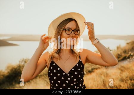 Frau in einem Hut und Brille in der Mitte von Wiese Stockfoto