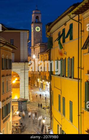 Fußgänger, die am Abend den Corso Italia mit dem Uhrturm im Hintergrund entlang gehen, Pisa, Toskana, Italien Stockfoto