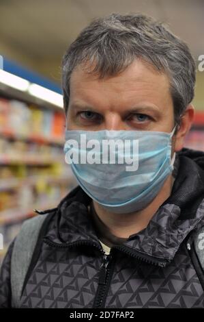 Porträt eines jungen Mannes mit einer medizinischen Maske in einem Supermarkt. Stockfoto