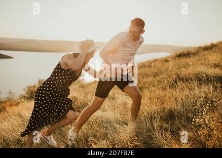 Mann und Frau, die bei Sonnenuntergang auf der Wiese spazieren Sommer in der Nähe des Sees Stockfoto