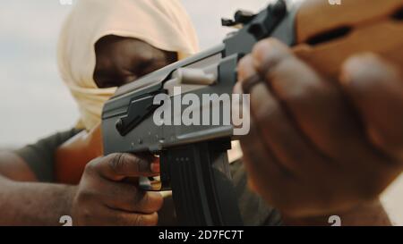 Konzept des Terrorismus. Rebellensoldat zielt mit einem AK-47 Maschinengewehr auf Ziele. Nahaufnahme. Hochwertige Fotos Stockfoto