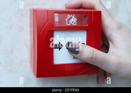 Menschliche Hände ziehen rote Feueralarme an den weißen Wänden entlang des Einkaufskorridors.das Konzept eines Bildes über Feueralarme in Gebäuden. Feuer Stockfoto