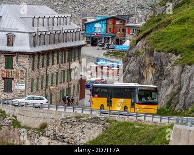 Gelber schweizer Bus auf der Straße beim geschlossenen Hotel Belvedere, Furka Pass, Schweiz. Stockfoto