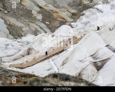 Man läuft zum Eingang der Eishöhle, Rhonegletscher bedeckt mit Platten, um das Eis vor dem Schmelzen über der Gletscherhöhle zu schützen, Belvedere, Schweiz Stockfoto