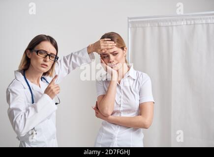 Doctor Frau misst die Temperatur des Patienten und ein Stethoskop am Hals Stockfoto