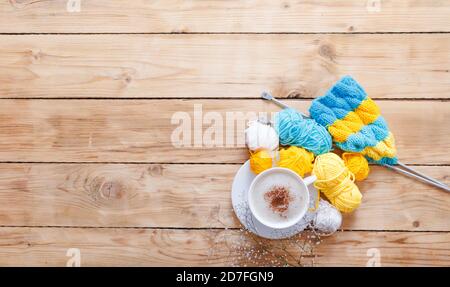 Garn in warmen Farben auf einem weißen Holzbrett. Gelb, blau, beige, weiß und grün. Der Beginn des Strickprozesses eines Damenpullovers. Weiblich Stockfoto