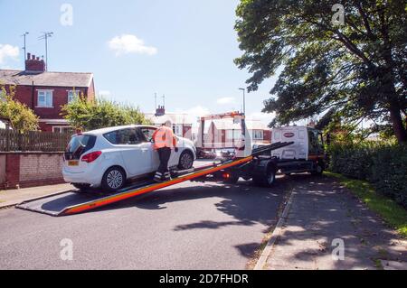 Mann trägt hohe Sichtbarkeits Sicherheitsjacke Laden Auto durch Winde Auf hydraulischem Flachbett des Bergung Fahrzeugs in beengten Raum Stockfoto