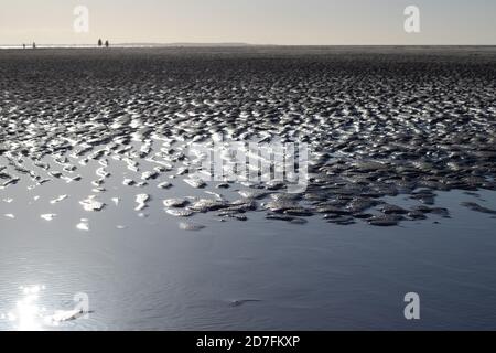 Texturen von Wasser und Wind auf dem Sand am Strand, Reflexionen im Wasser Stockfoto