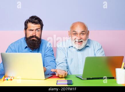Generation von Menschen und Stadien des Aufwachsens. Älterer Mann, der mit seinem Sohn einen Laptop benutzt. Älterer Mann, der mit seinem erwachsenen Sohn einen Laptop benutzt. Stockfoto