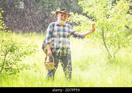 Alter Mann, der läuft. Opa Rentner. Senior Wandern im Wald. Sommer und Hobbys. Großvater mit Korb von Pilzen und eine überraschende Gesichtsbehandlung Stockfoto