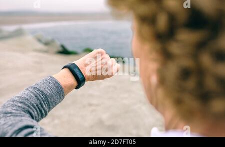 Ältere Frau, die eine intelligente Uhr sucht Stockfoto