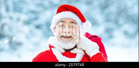 Lieferung weihnachtsgeschenke. Winter Weihnachten Grußkarte. Weihnachtsmann mit großer Tasche. Weihnachtsmann mit Tasche zu Fuß im Winter. Stockfoto