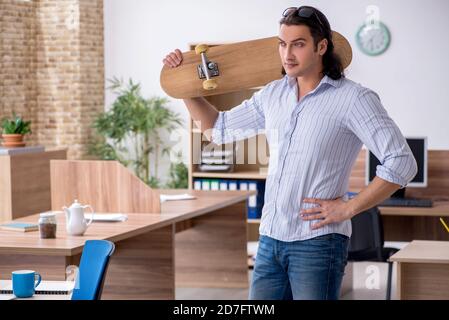 Junge Mitarbeiterin mit Skateboard im Büro Stockfoto