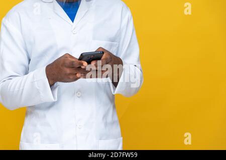 Nahaufnahme eines jungen afrikaners im Labormantel Über sein Telefon Stockfoto
