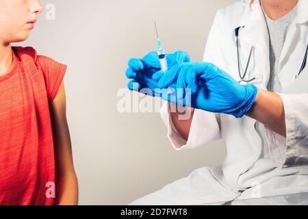 Arzt impfen Kind für Coronavirus in der Klinik. Spritze mit Handschuhen geschützte Hände. Stockfoto