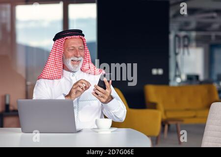 Arabischer Geschäftsmann zuversichtlich und lächelnd im Büro mit Laptop. Stockfoto