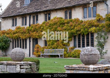 Sandsteinhaus mit Gartenbank, im hübschen Dorf Biddestone bei Chippenham in den Cotswolds, Wiltshire UK. Fotografiert im Herbst. Stockfoto