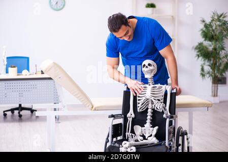 Männlicher Arzt und Skelett im Rollstuhl Stockfoto