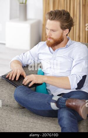 Ein Mann tippt die Tastatur auf dem Sofa Stockfoto