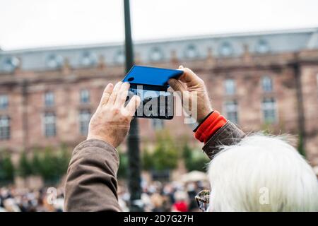 Straßburg, Frankreich - 19. Oktober 2020: Frau, die mit dem Smartphone fotografiert.Ort Kleber, um dem Geschichtslehrer Samuel Paty zu Tribut zu zollen, der am 16. Oktober enthauptet wurde, nachdem er Karikaturen gezeigt hatte Stockfoto