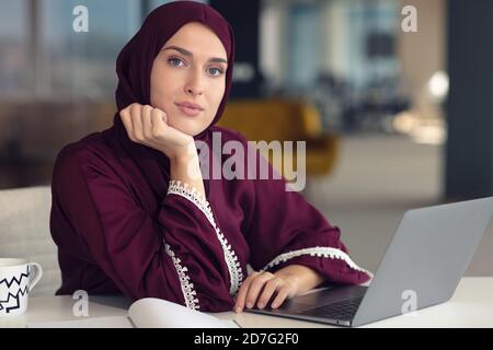 Nachdenkliche arabische Geschäftsfrau, die am Arbeitsplatz im Büro sitzt Stockfoto