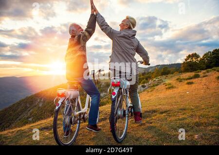 Aktives Seniorenpaar feiert Erfolg bei schönem Sonnenuntergang. Stockfoto
