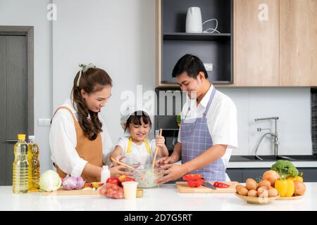 Junge asiatische Liebe Familie bereiten Salat Gemüse auf dem Tisch In der Küche, die Vater und Mutter lehren Tochter Kochen Essen am Tag um Stockfoto