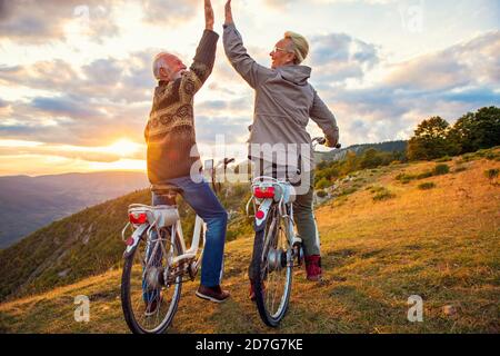 Aktives Seniorenpaar feiert Erfolg bei schönem Sonnenuntergang. Stockfoto