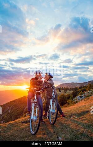 Aktives Senior-Paar auf Fahrrädern, die Herzform mit Händen und küssen. Stockfoto