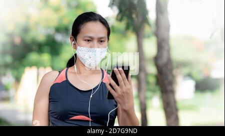Asien Frau trägt Maske Joggen im Park Stockfoto