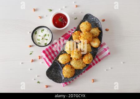 Sabudana vada oder Sago frittierte Monteure serviert mit Curd oder Joghurt und Ketchup auf weißem Holzhintergrund, beliebtes Fastenrezept aus Indien Stockfoto