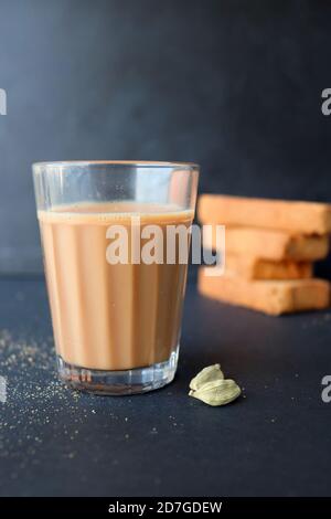 Tea Time Snack - gesunde Weizen Zwieback serviert mit indischen heißen Masala Tee, auf schwarzem Hintergrund mit dem Kardamom. Auch bekannt als Mumbai Cutting Chai. Stockfoto