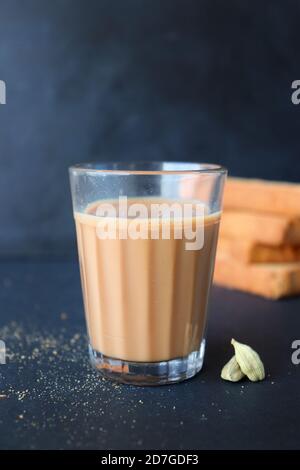 Tea Time Snack - gesunde Weizen Zwieback serviert mit indischen heißen Masala Tee, auf schwarzem Hintergrund mit dem Kardamom. Auch bekannt als Mumbai Cutting Chai. Stockfoto