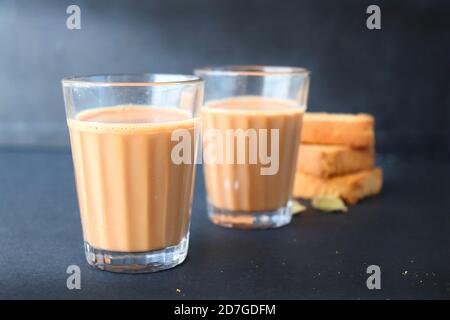 Tea Time Snack - gesunde Weizen Zwieback serviert mit indischen heißen Masala Tee, auf schwarzem Hintergrund mit dem Kardamom. Auch bekannt als Mumbai Cutting Chai. Stockfoto