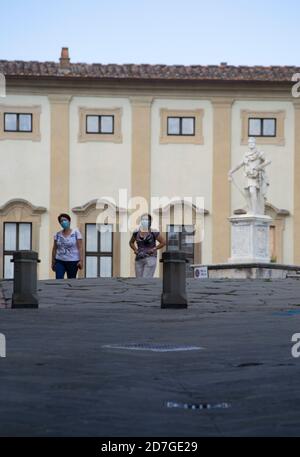 Zwei maskierte Touristen schlendern durch die Stadt Arezzo Stockfoto
