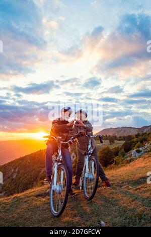 Aktives Senior-Paar auf Fahrrädern, die Herzform mit Händen und küssen. Stockfoto