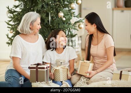 Asiatische Mutter und ihre Tochter mit Enkelin gratuliert einander Mit Weihnachten und Geschenken auf dem Boden sitzen Stockfoto