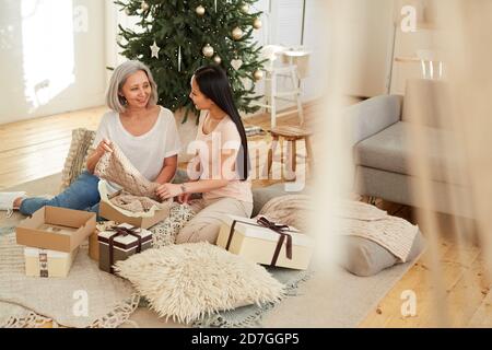Asiatische schöne Mutter Eröffnung Weihnachtsgeschenke zusammen mit ihr Tochter Auf dem Boden im Zimmer Stockfoto