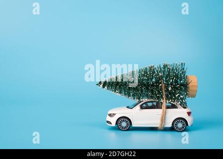 Frohe Christamas Konzept. Seitenprofil Nahaufnahme Foto von Mini-Spielzeug weiß stilvolle moderne Auto tragen Tannenbaum im Schnee auf der Oberseite des Daches isoliert o Stockfoto