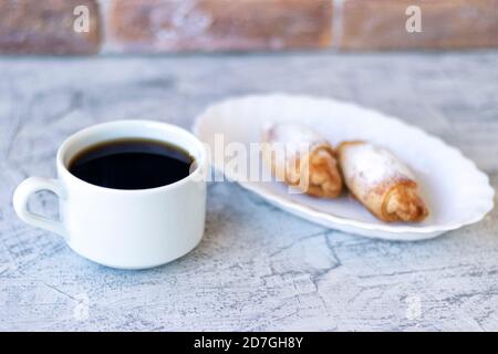 Italienisches Frühstück mit Croissants und Kaffee. Zwei Croissants und Kaffee auf strukturiertem Tisch. Weichfokus Stockfoto