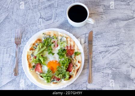 Italienisches Frühstück mit Kaffee. Piadina mit Ei, Tomaten und Salat. Köstliches Frühstück mit Kaffee auf strukturiertem Tisch serviert. Draufsicht. Weichfokus Stockfoto