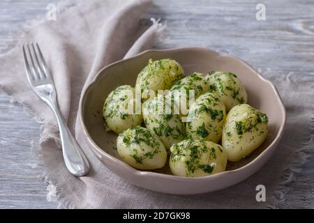 Gekochte Kartoffeln mit Kräuterbutter und Knoblauch auf dem Holztisch, selektiver Fokus Stockfoto