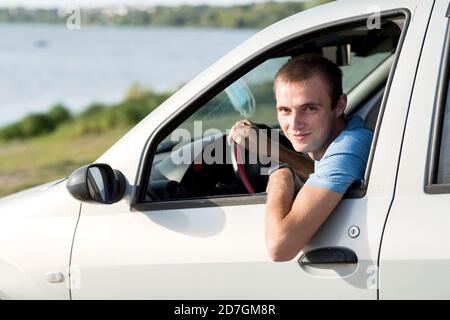 Ein junger Mann schaut aus dem Fenster seines Autos. Stockfoto