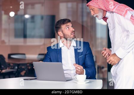 Reifer Geschäftsmann aus dem Nahen Osten, der Ghoutra in der Sitzung trägt Stockfoto