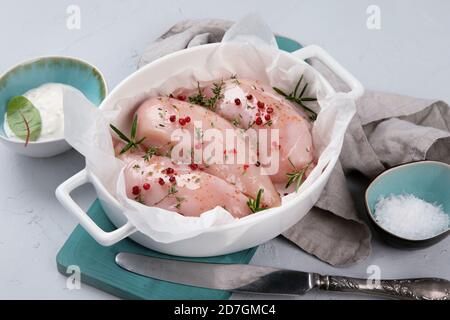 Frisches, rohes Hühnerfilet mit Gewürzen, Kräutern und Gemüse. Abendessen wird vorbereitet. Stockfoto